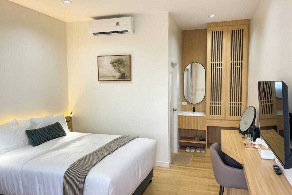 Une chambre d’hôtel équipée d’un lit, d’un bureau, d’un miroir et d’une armoire.