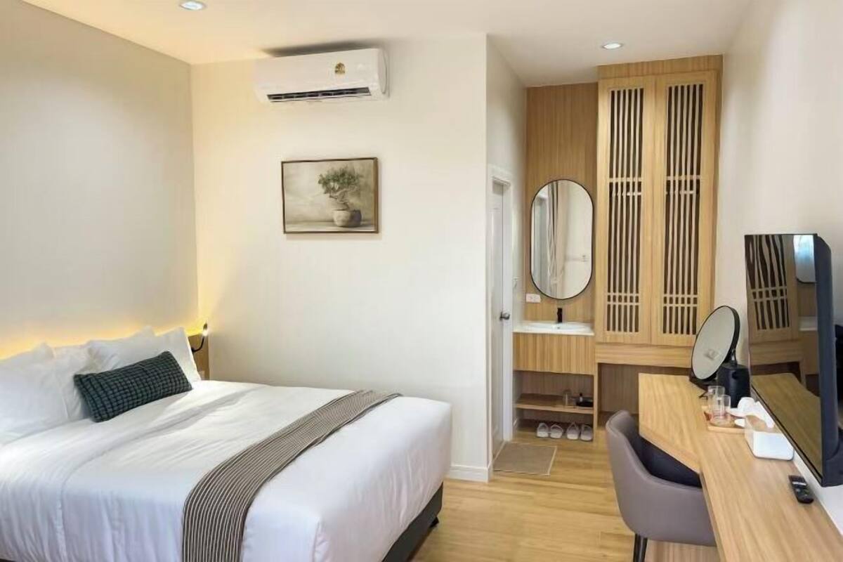 Une chambre d’hôtel comprenant un lit, un bureau avec un ordinateur, un miroir et une armoire avec des portes coulissantes.