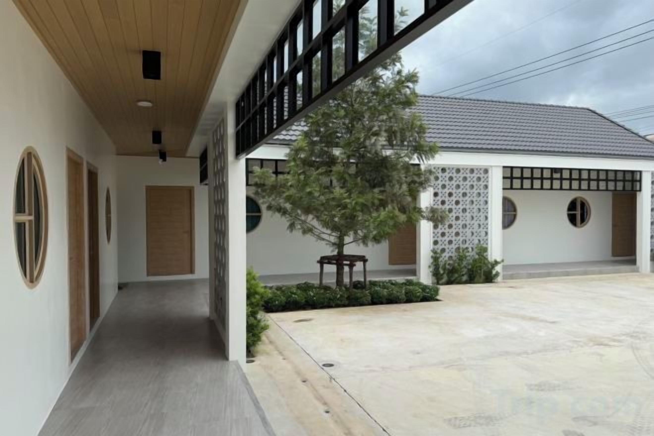 Un bâtiment doté d’une galerie couverte, d’un arbre et d’une cour.
