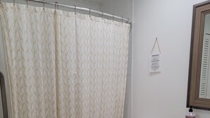 Une salle de bain équipée d’un rideau de douche, de toilettes, d’un lavabo et d’un porte-serviettes.