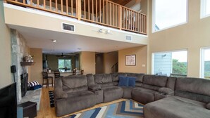 A spacious living room with a large sectional sofa, a fireplace, and a dining area. - Cliffside at Canyon Lake - Monthly Rental (New Braunfels)