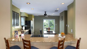 A kitchen with granite countertops, wooden chairs, and a ceiling fan. - Cliffside at Canyon Lake - Monthly Rental (New Braunfels)