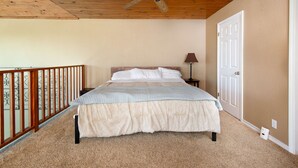 A bedroom with a bed, a ceiling fan, a nightstand, a lamp, and a door. - Cliffside at Canyon Lake - Monthly Rental (New Braunfels)