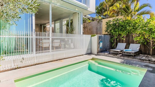 Une maison moderne dotée d’une piscine, d’un patio couvert et d’un jardin clos.