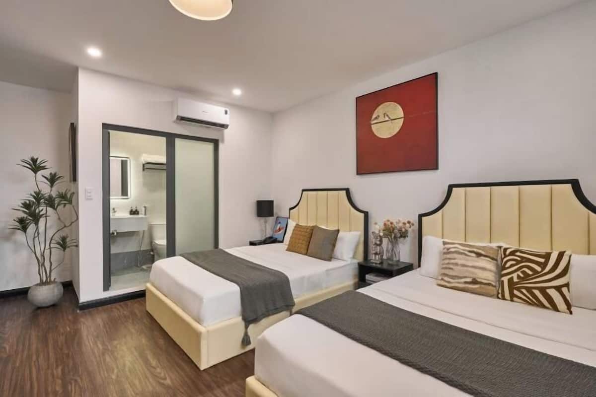 A hotel room with two beds, a bathroom, and a large mirror.