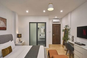 A modern bedroom with a bed, bedside table, lamp, TV, desk, chair, and a plant. - Venus Secret Hotel Aeon Bình Tân (Ho Chi Minh City)