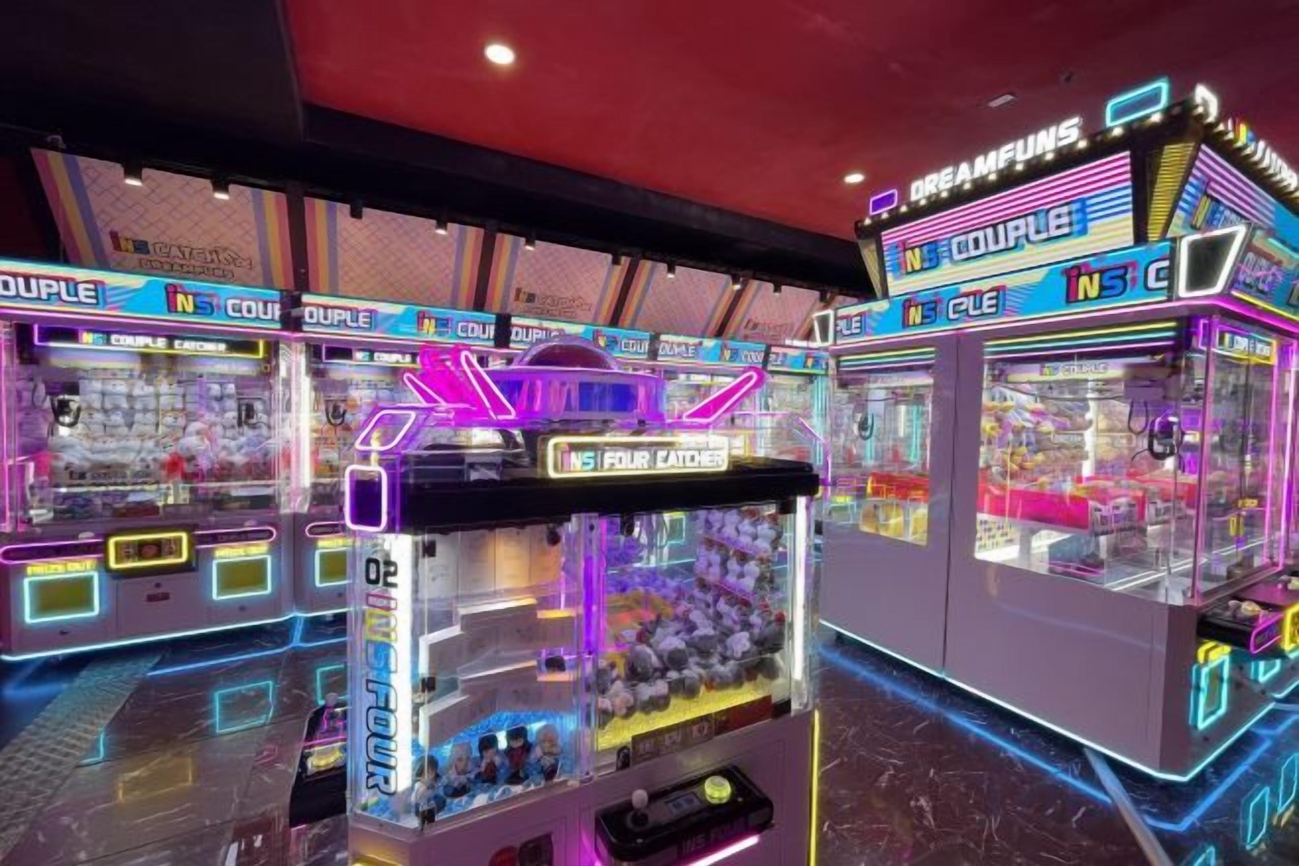 A row of claw machines with neon signage, arranged in a row.