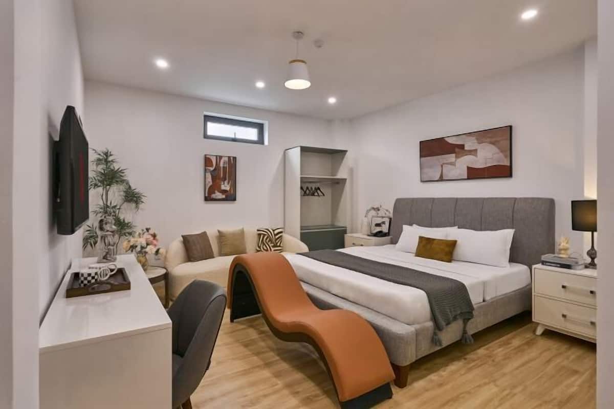 A modern bedroom with a bed, bedside tables, a desk, a chair, a wardrobe, and artwork on the walls.