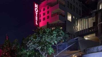 A hotel with a prominent red sign, a modern architectural style, and a well-lit facade.
