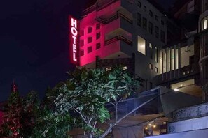 Un hotel con un llamativo letrero rojo, estilo arquitectónico moderno y fachada bien iluminada.