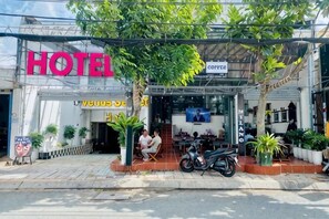 A hotel with a prominent 'HOTEL' sign, outdoor seating area, and a motorcycle parked outside. - Venus Secret Hotel Aeon Bình Tân (Ho Chi Minh City)