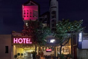 A hotel with a prominent neon sign, outdoor seating area, and a visible entrance. - Venus Secret Hotel Aeon Bình Tân (Ho Chi Minh City)
