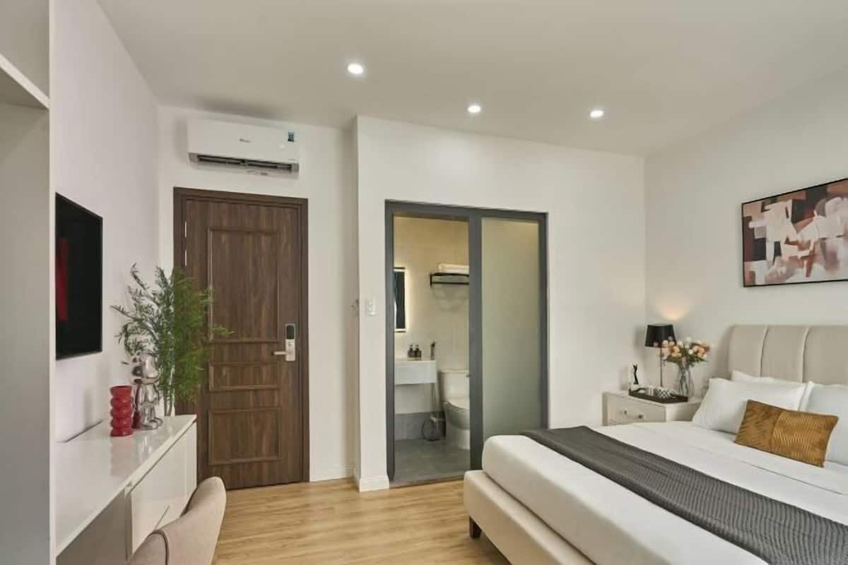 A modern bedroom with a bed, bedside table, and a wall-mounted TV.