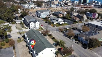 Vista aérea de una zona residencial con un gran edificio blanco de techo verde, rodeado de casas más pequeñas y una calle.