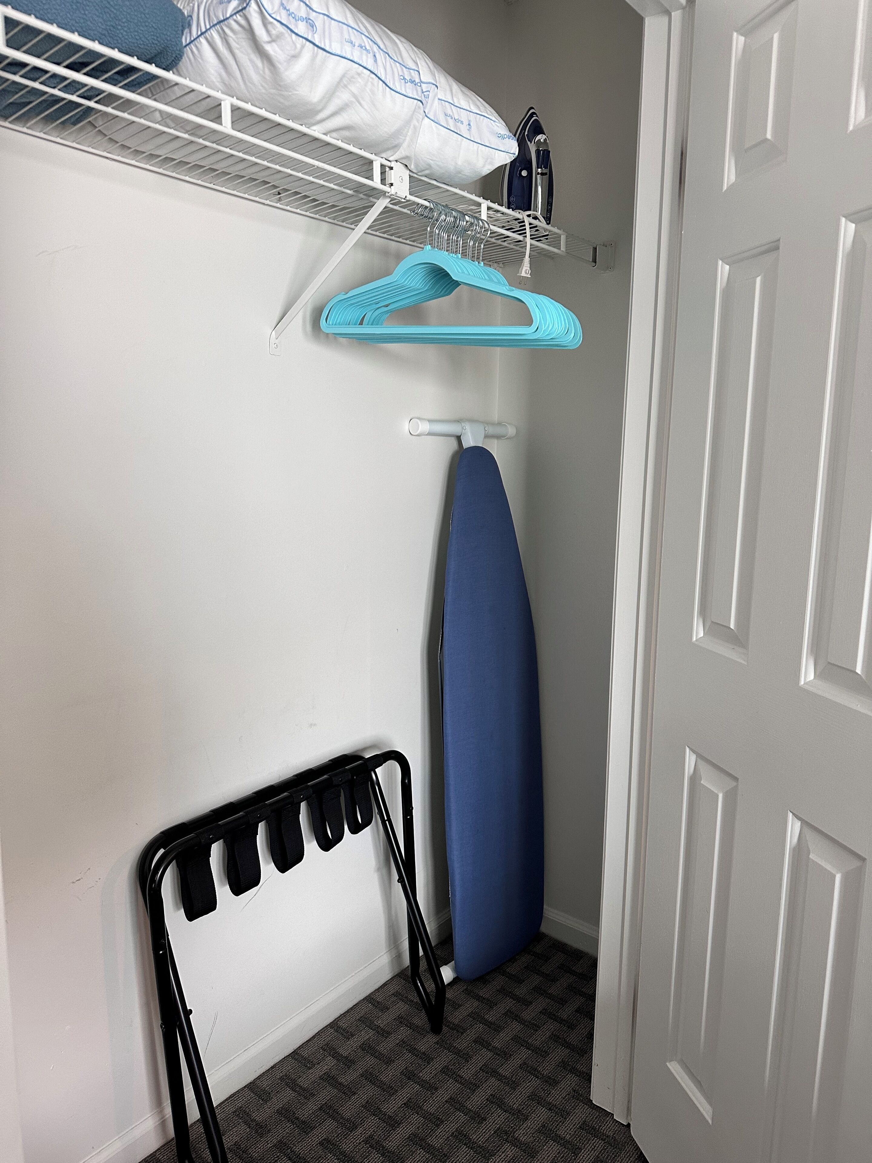 Un espace dédié à la lessive, équipé d’un étendoir, d’une planche à repasser et de cintres pour suspendre les vêtements.