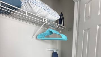 Un espace dédié à la lessive, équipé d’un étendoir, d’une planche à repasser et de cintres pour suspendre les vêtements.