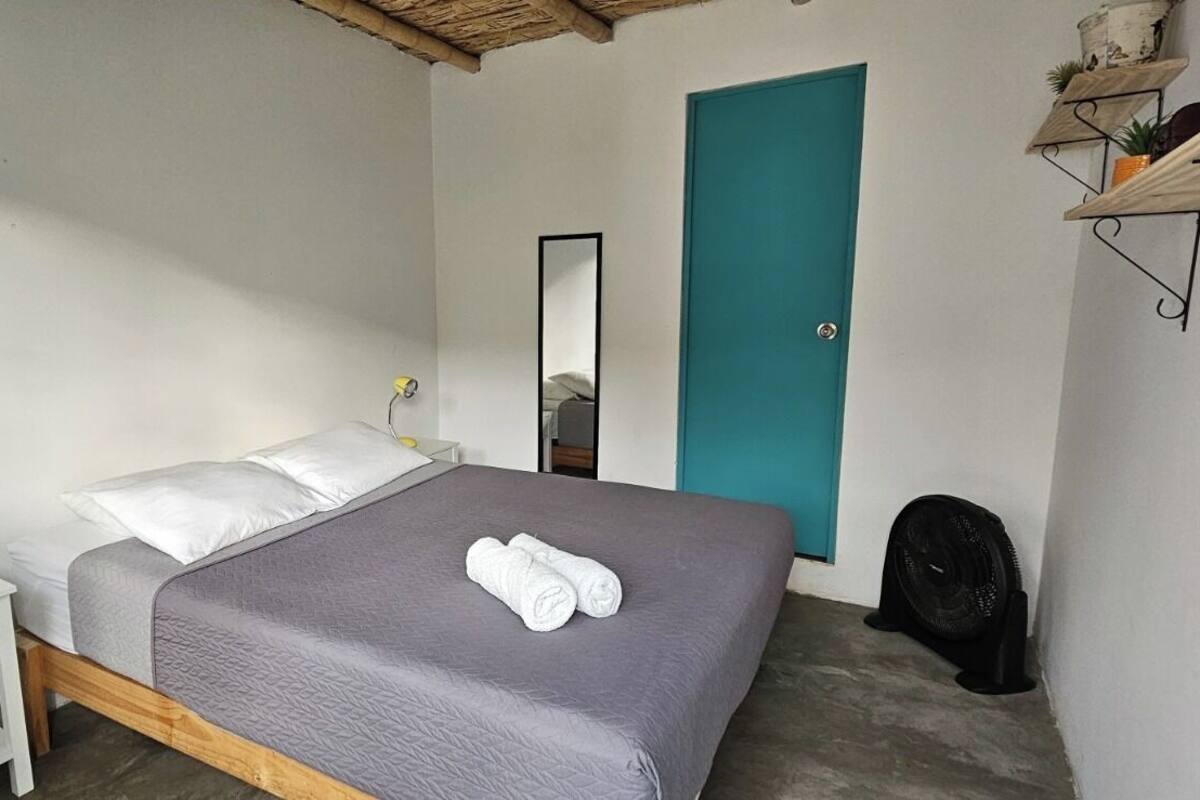 A bedroom with a bed, bedside table, lamp, and a door.