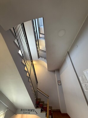 Un interno moderno con una scala che conduce ai piani superiori, un'area reception e un cartello a parete.