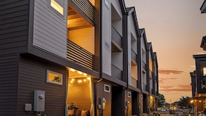 Une rangée d’immeubles modernes à plusieurs étages, dotés de balcons, d’espaces de repos en plein air et d’un sentier aménagé.