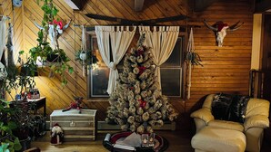 A cozy living room with a Christmas tree, wooden walls, a sofa, and a decorative skull on the wall.