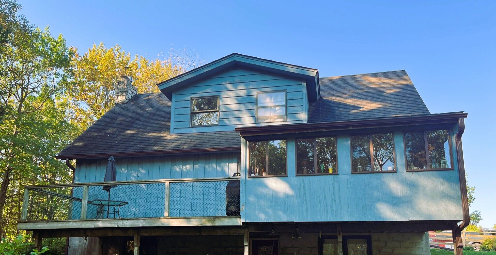 Une maison à deux étages avec un balcon et une cheminée en pierre.