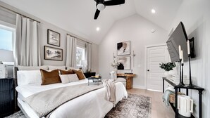 A bedroom with a large bed, a ceiling fan, a TV, and artwork on the walls. - The Boro Suite I 3BR Near Downtown & MTSU w/ Ping Pong (Murfreesboro)