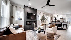 A modern living room with a sofa, ottoman, and a fireplace. - The Boro Suite I 3BR Near Downtown & MTSU w/ Ping Pong (Murfreesboro)