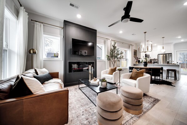 Un salon moderne avec un canapé, un pouf et une cheminée.