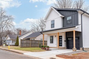 Une maison d’habitation à deux étages, dotée d’un porche à l’avant, d’une porte d’entrée noire et d’une cheminée bien visible.