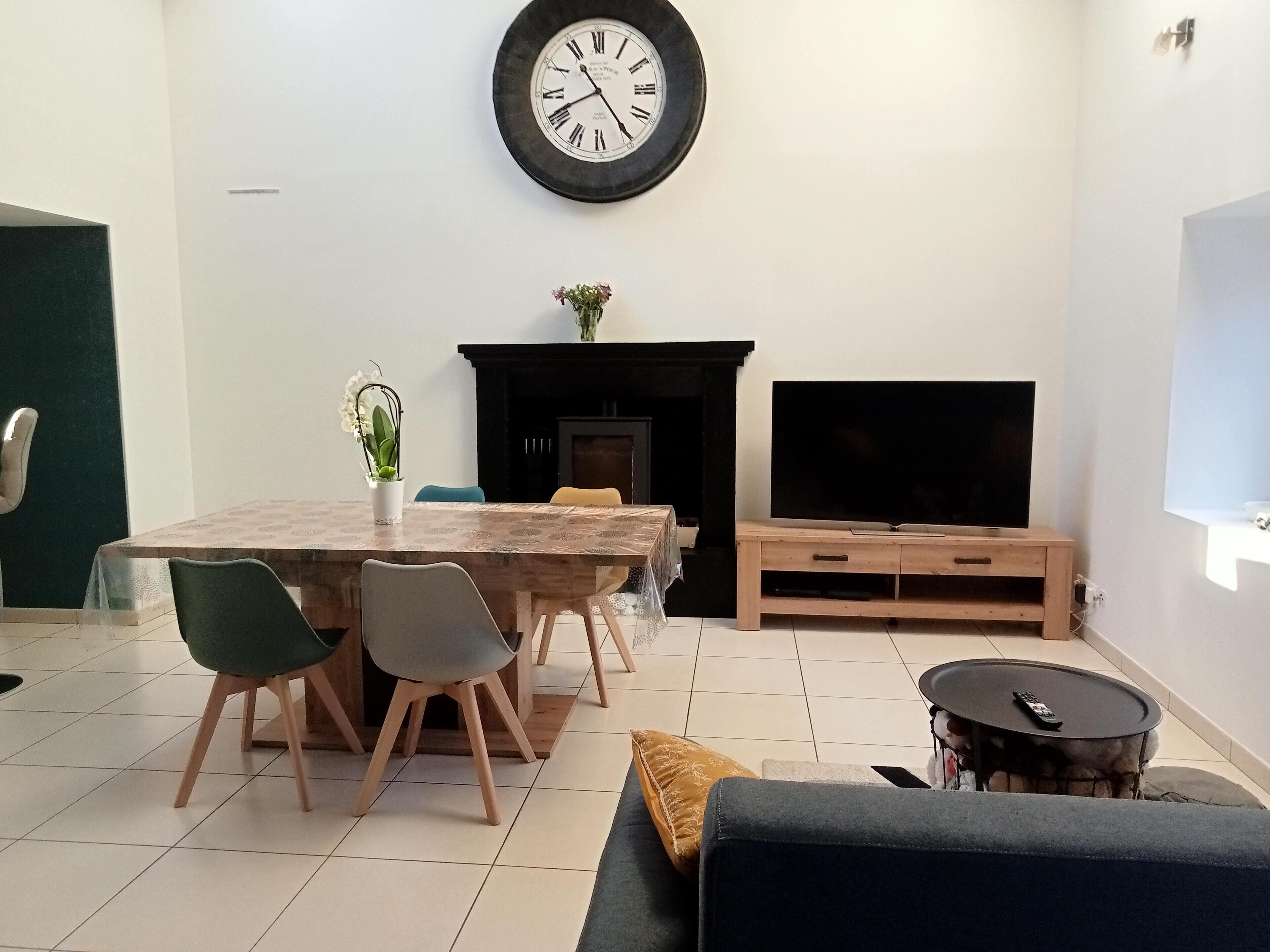 A living room with a dining table, chairs, a sofa, a TV, and a fireplace.