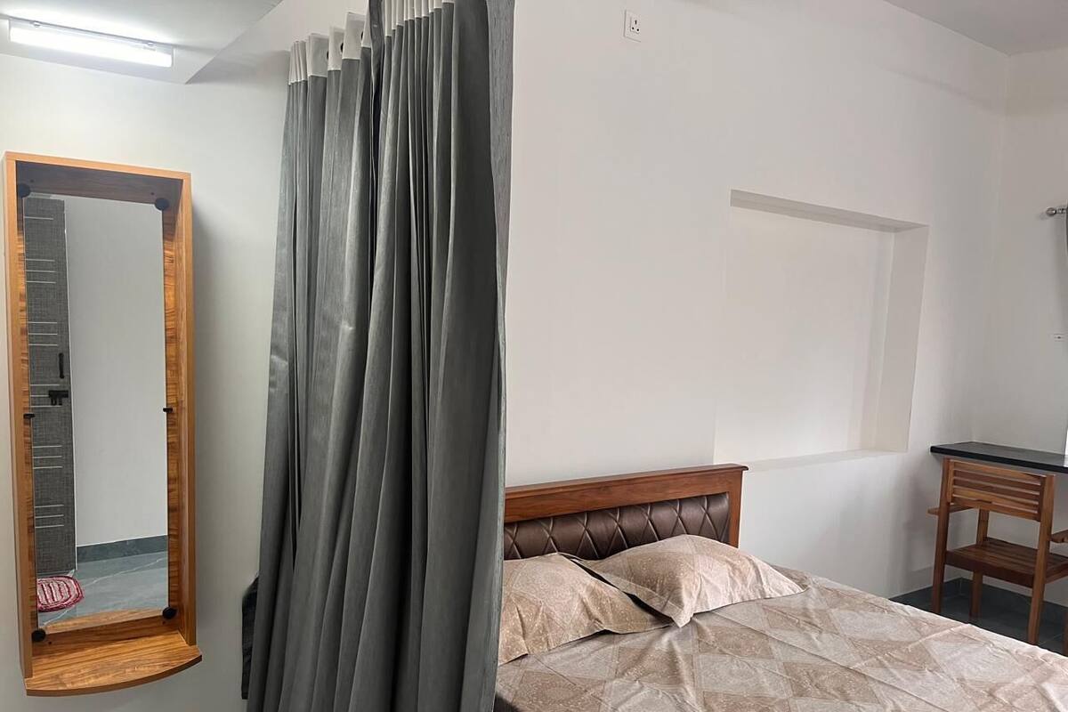 A bedroom with a bed, a wooden headboard, a mirror, and a desk.