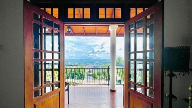 Una porta in legno aperta che dà su un balcone con vista su un paesaggio.