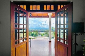 An open wooden door leading to a balcony with a view of a landscape. - Villa Avora Ridge (Kandy)