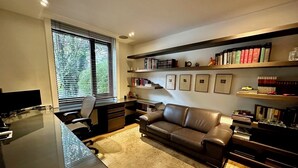 Un bureau moderne, aménagé dans une pièce de la maison, avec un bureau, un ordinateur et un canapé en cuir. On y trouve également des étagères remplies de livres et d’objets décoratifs.