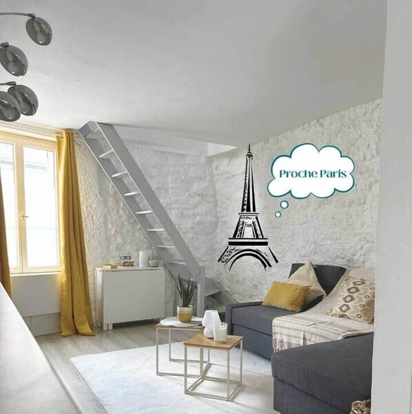 A modern living room with a staircase, a sofa, a coffee table, and a window with curtains.