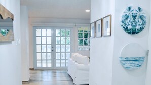 A hallway with a patterned floor, a white couch, and a door leading to a balcony. - Beachfront Modern Apt with Direct Sand Access in Sunny Rincon - Villa Sanfe (Rincón)