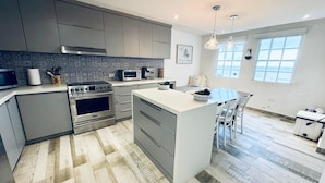 A modern kitchen with grey cabinets, stainless steel appliances, and a large island. - Beachfront Modern Apt with Direct Sand Access in Sunny Rincon - Villa Sanfe (Rincón)