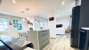 A modern kitchen with a large island, pendant lights, and a view to the dining area. - Beachfront Modern Apt with Direct Sand Access in Sunny Rincon - Villa Sanfe (Rincón)
