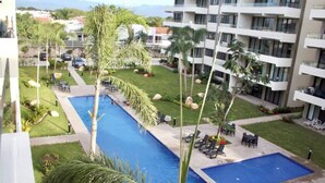 A hotel with a large outdoor swimming pool surrounded by palm trees and lounge chairs. - Cozy Family Condo - Pool & terrace - 10 minute to the beach - Nuevo Vallarta (Nuevo Vallarta)