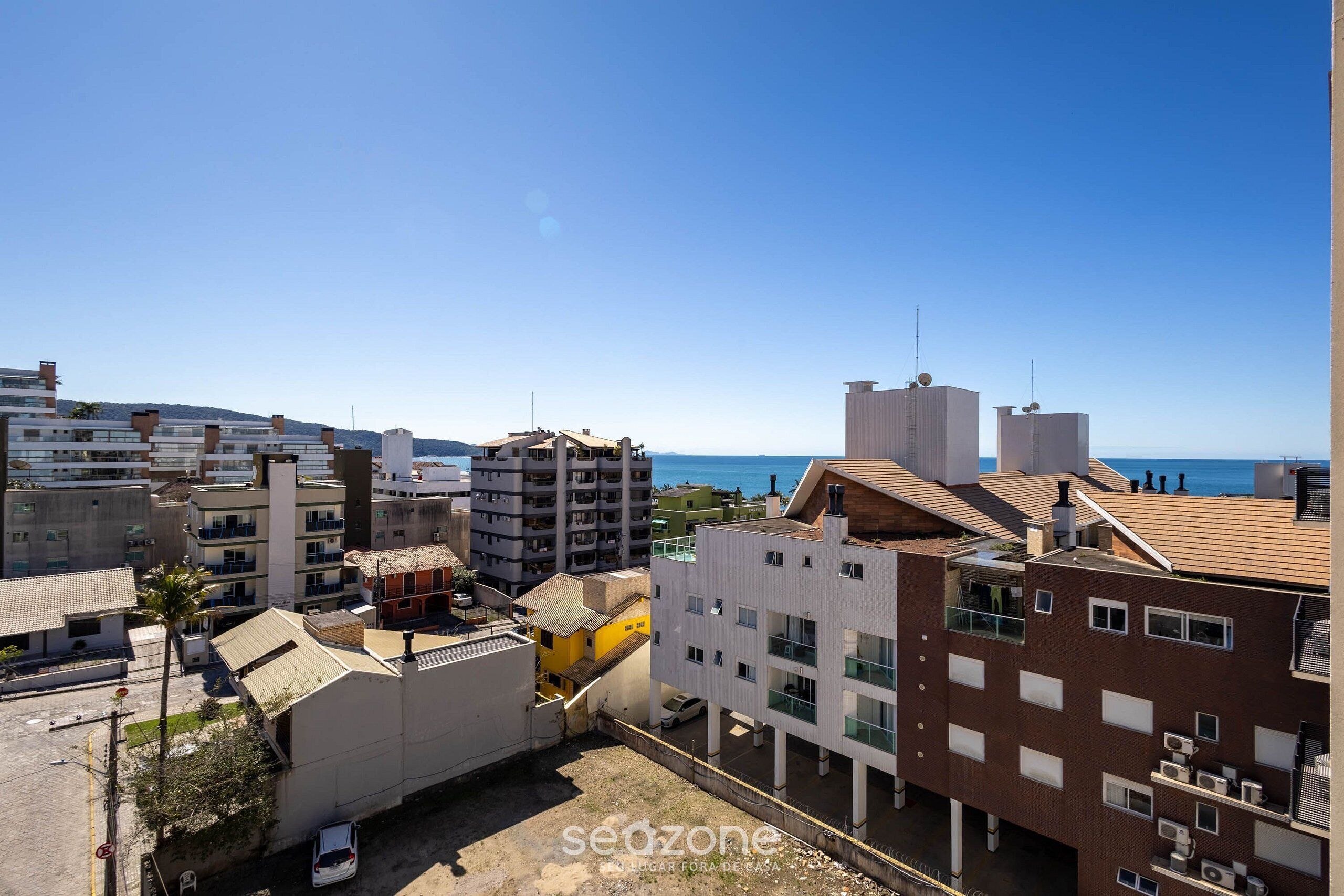 A coastal urban area with multi-story buildings, some with balconies, and a clear view of the sea.