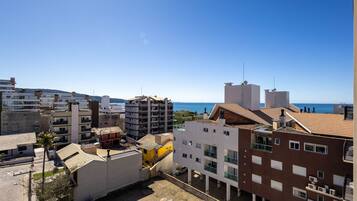 A coastal urban area with multi-story buildings, some with balconies, and a clear view of the sea.