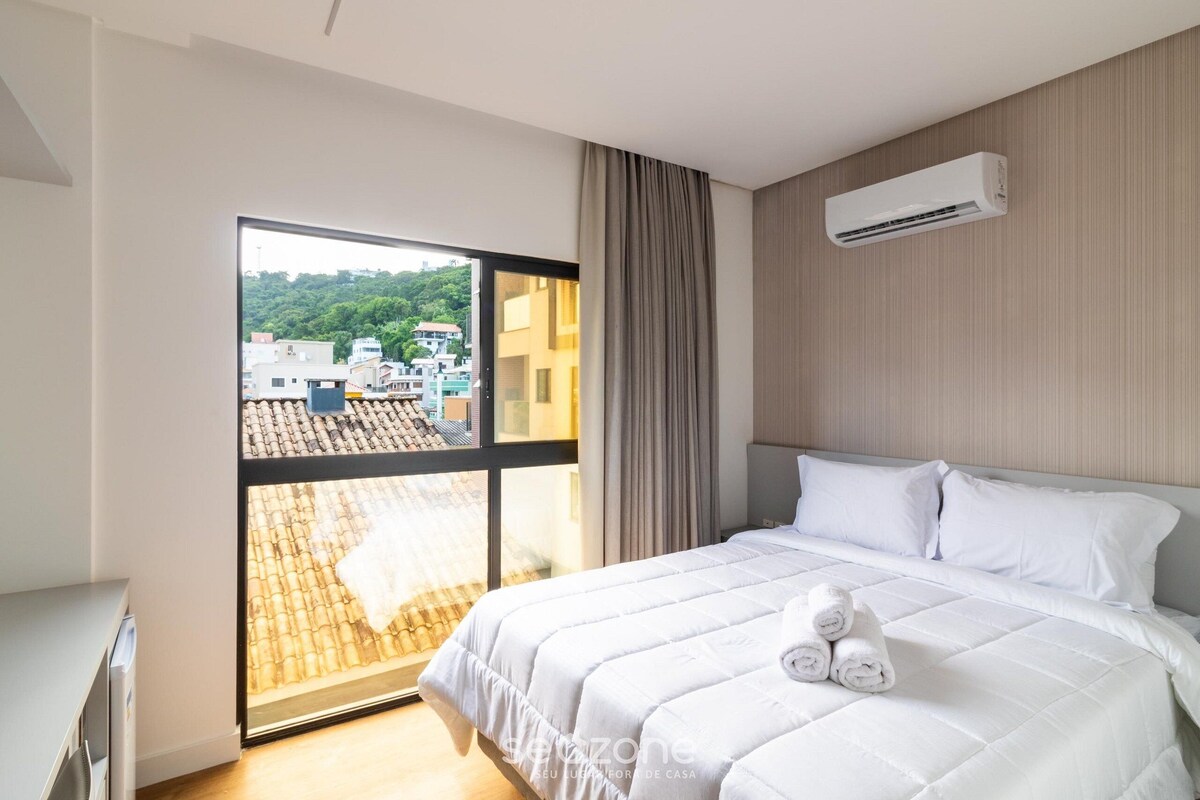 Una habitación de hotel con una cama, una ventana y un equipo de aire acondicionado.
