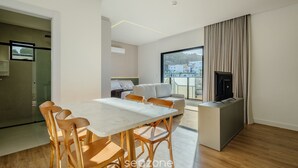Ein modernes Wohnzimmer mit Essbereich, einer Couch, einem Fernseher und einem Kamin.