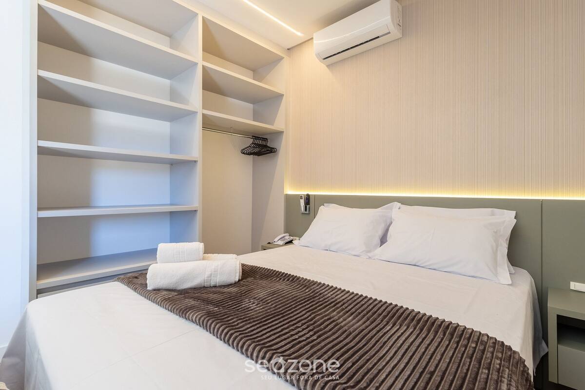 A hotel room with a bed, a wardrobe, and a nightstand.