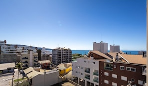 A coastal urban area with multi-story buildings, some with balconies, and a clear view of the sea. - Apartments in a Building With a Pool, 180m From the Beach in Bombinhas - Sfrs (Bombinhas)