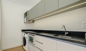 A modern kitchen with a built-in oven, microwave, and a stainless steel sink. - Apartments in a Building With a Pool, 180m From the Beach in Bombinhas - Sfrs (Bombinhas)