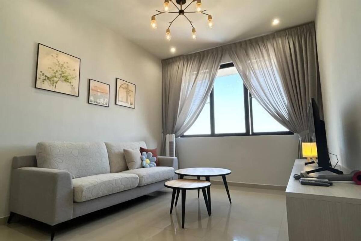 A modern living room with a sofa, two round tables, and a TV on a stand.