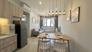 A modern kitchen with a dining area, wooden cabinets, and a built-in refrigerator. - Cozy 2BR Sky Pool & Panoramic Views 1-6 Guests (Gelugor)