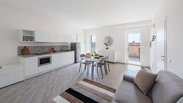 A modern apartment with a kitchen, dining area, and living room. - Spacious 2 bedroom apartment with pool (Soiano del Lago)