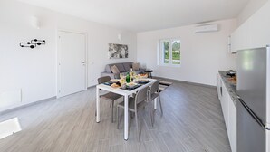 A modern kitchen with a dining area, a built-in oven, and a large window providing natural light. - Spacious 2 bedroom apartment with pool (Soiano del Lago)